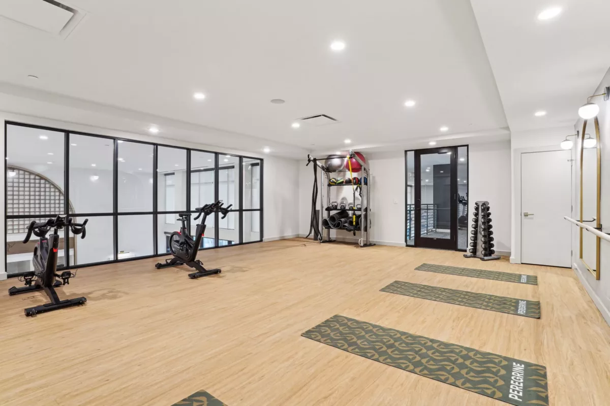 Yoga and cycling studio with wood flooring and wall-mounted fitness gear.