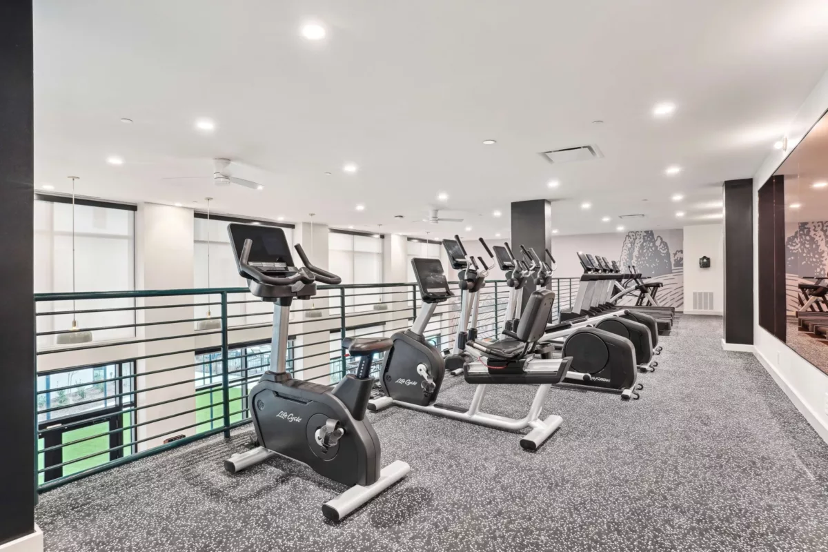 Cardio equipment on upper level of a gym with treadmills and exercise bikes in a row.
