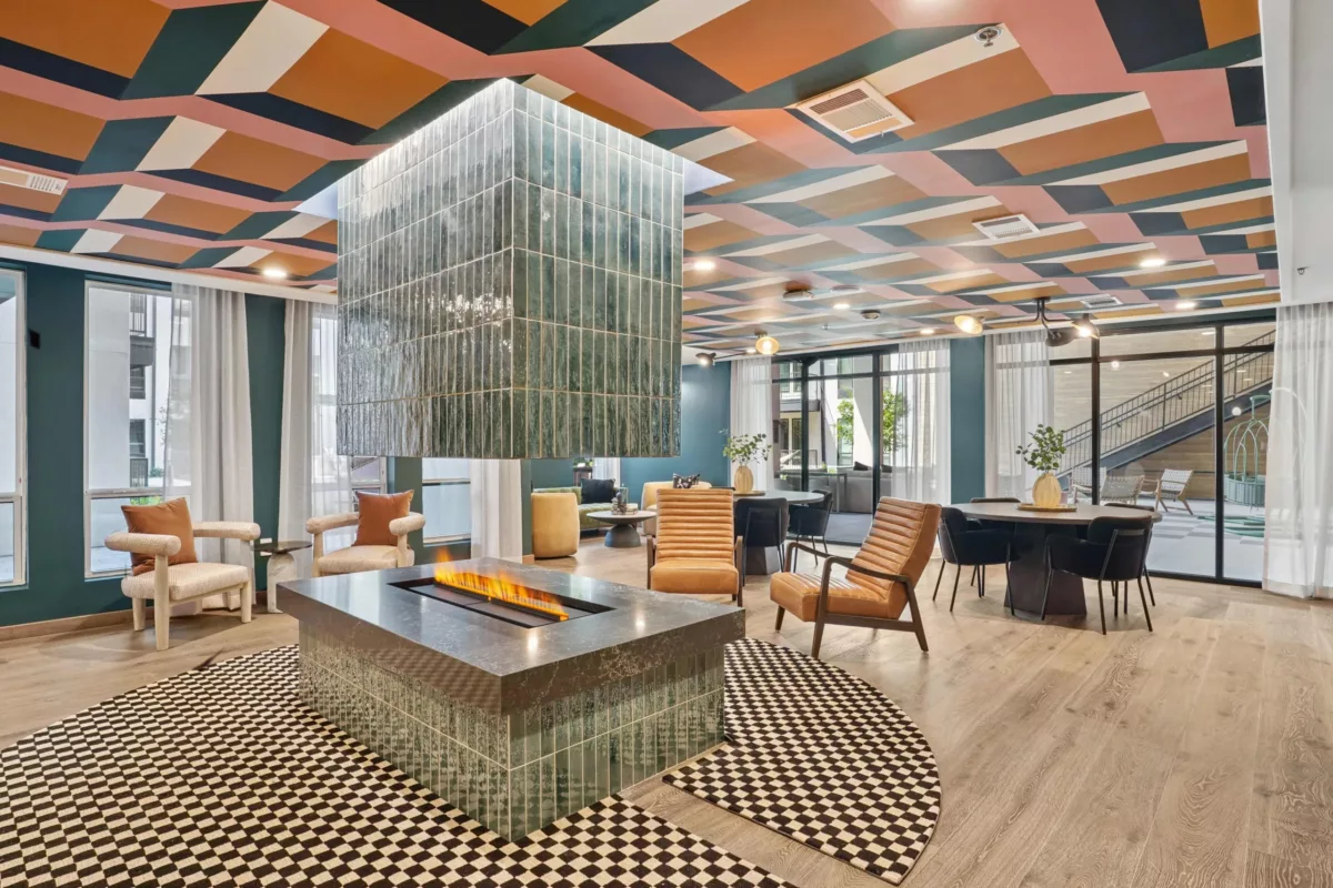 Vibrant lounge with geometric ceiling, modern fireplace, and mixed seating areas.