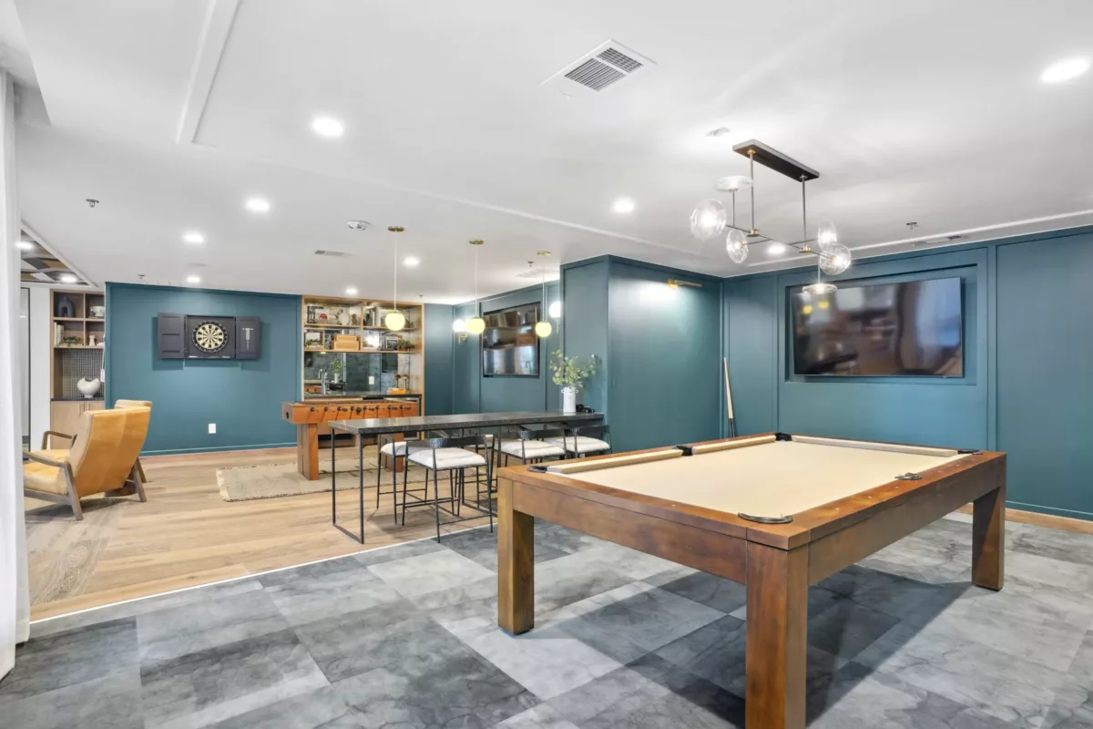 Game room with pool table, foosball, dart board, and large wall TV.