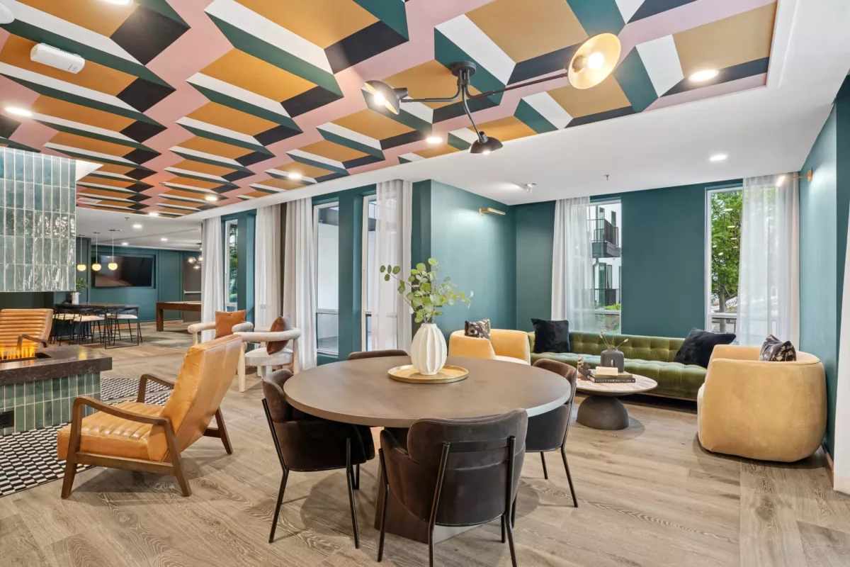 Lounge with bold ceiling pattern, velvet seating, and round dining table.