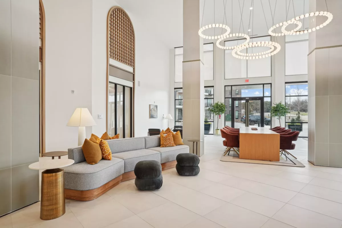 Spacious lobby with tall windows, curved sofa, ring lights, and warm accent furniture.
