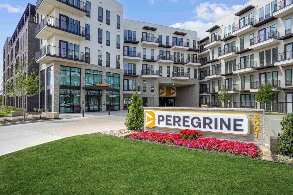 Modern apartment exterior with glass entry, balconies, and Peregrine sign in front.