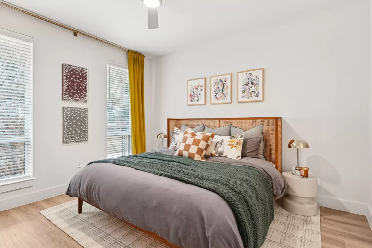 Cozy bedroom with checkered and floral pillows, woven headboard, and bold yellow drapes.