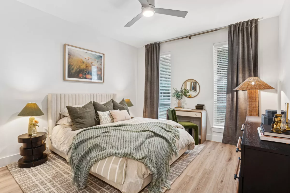 Bedroom with tufted headboard, layered bedding, and a writing desk by window.