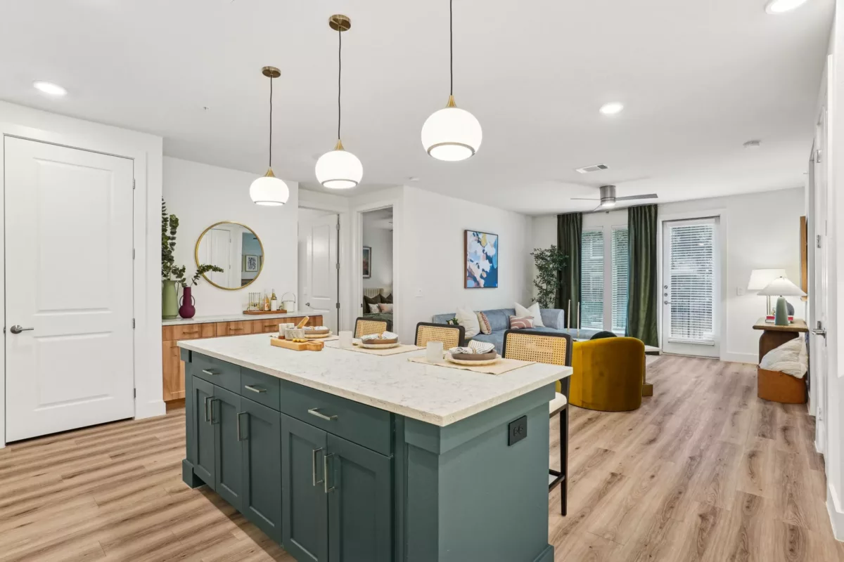 Open-concept living and kitchen area with island and pendant lights.