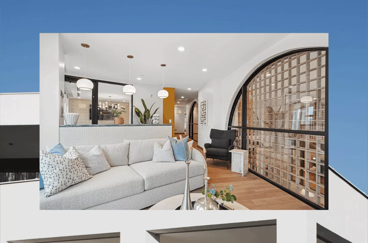 Photo of a lounge with a light gray couch, arched window, and white walls, overtop of another photo of an apartment building.